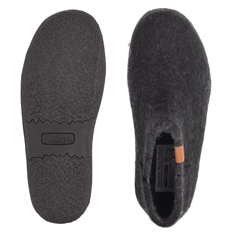 Due pantofole Green Comfort nere in feltro di lana, una mostra la suola in gomma antiscivolo, l'altra la parte superiore